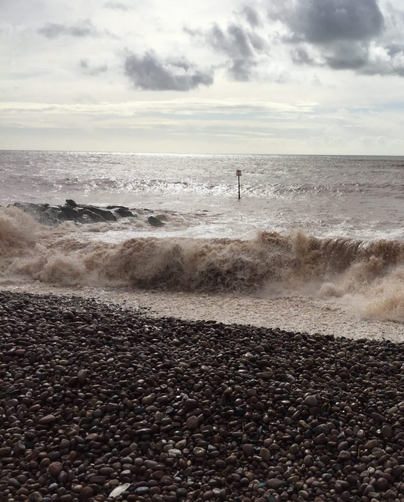 foamy waves crashing into a pebble beach